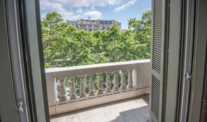 Un balcon orné d’une balustrade, un ciel dégagé et des bâtiments en arrière-plan.