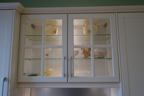 Un mueble blanco con puertas de cristal que contiene varios objetos de cerámica.