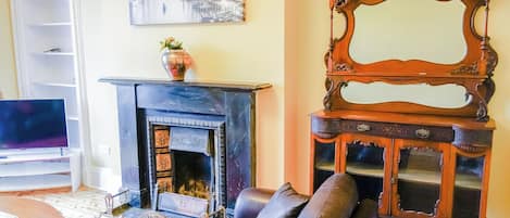 A living room with a fireplace, a sofa, a television, and a mirror.