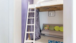 A room with a bunk bed, a ladder, a sofa with colorful cushions, and a framed picture on the wall. - Beautifully Modernised New Town Home for 5 (Edinburgh)
