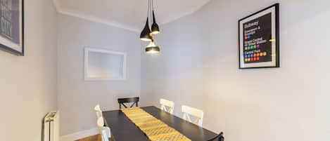 A dining area with a table, chairs, a pendant light, and a subway map on the wall.