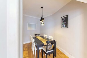 A dining area with a long table, chairs, pendant lighting, and a subway map on the wall.