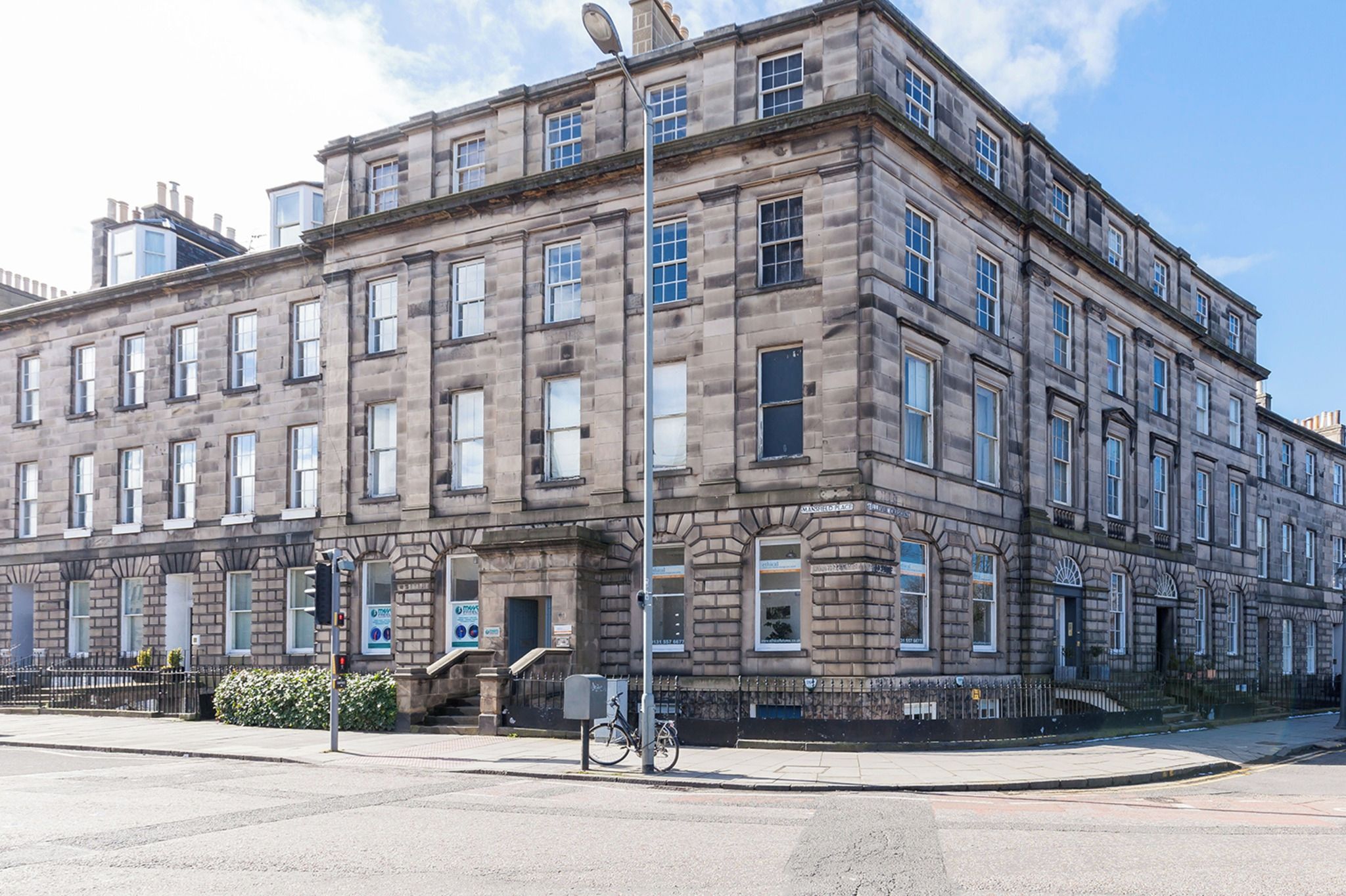 Un immeuble à étages doté d’un style architectural classique, caractérisé par une façade symétrique avec des fenêtres régulièrement espacées et une entrée centrale.