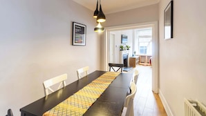 A dining area with a long table, chairs, a black table runner, pendant lighting, and a framed subway map on the wall. - Beautifully Modernised New Town Home for 5 (Edinburgh)