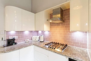A kitchen with white cabinets, a gas stove, a toaster, and a coffee maker.