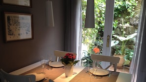 A dining table set for two with white chairs, a vase of flowers, and wine glasses. - ALMADRAVASOL·COM - Fantastic terraced house with parking, wifi and climatisation (Roses)