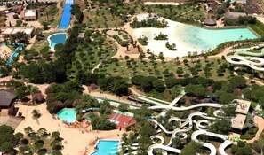 Vue aérienne d’un complexe hôtelier doté de plusieurs piscines, d’un grand parc aquatique et d’une plage.