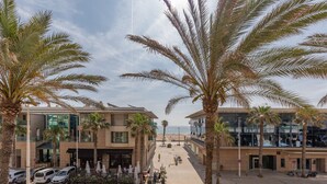 Een hotel met een centrale binnenplaats, palmbomen en uitzicht op het strand.