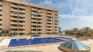 Een hotel met een zwembad, meerdere balkons en uitzicht op zee.