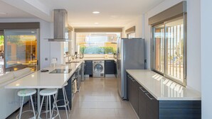 Een moderne keuken met een centraal eiland, ingebouwde apparatuur en grote ramen.