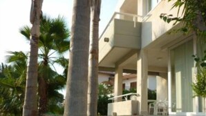 A modern two-story building with a balcony and a covered outdoor seating area.