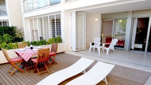 An outdoor patio with a table set for dining, lounge chairs, and a covered area. - Tierra de Mar 60 by homeprive (Denia)