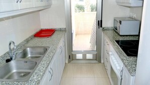 A kitchen with a double sink, a microwave, and a red tray on the counter. - Tierra de Mar 60 by homeprive (Denia)