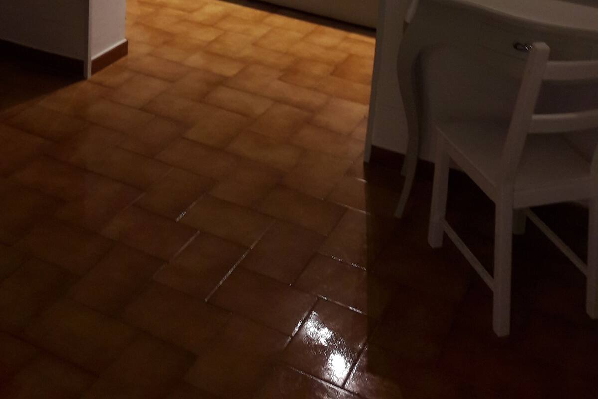 Un dormitorio con una cama, una mesita de noche, una silla y una pequeña mesa con lámpara.