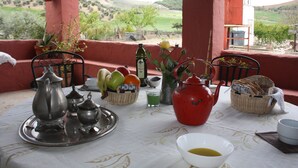 A table set with tea service, fruit, and a view of the countryside. - River Bed Seat (pruna)