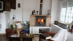 A cozy room with a brick fireplace, wooden furniture, and a window with decorative iron bars. - River Bed Seat (pruna)