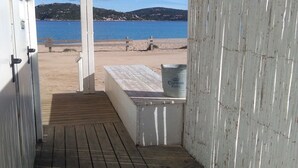 A wooden deck leading to a beach with a view of the sea and hills.