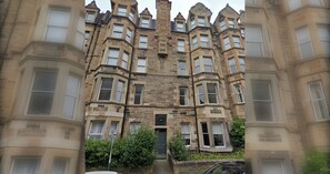 A multi-story building with a stone facade, multiple windows, and a central entrance.
