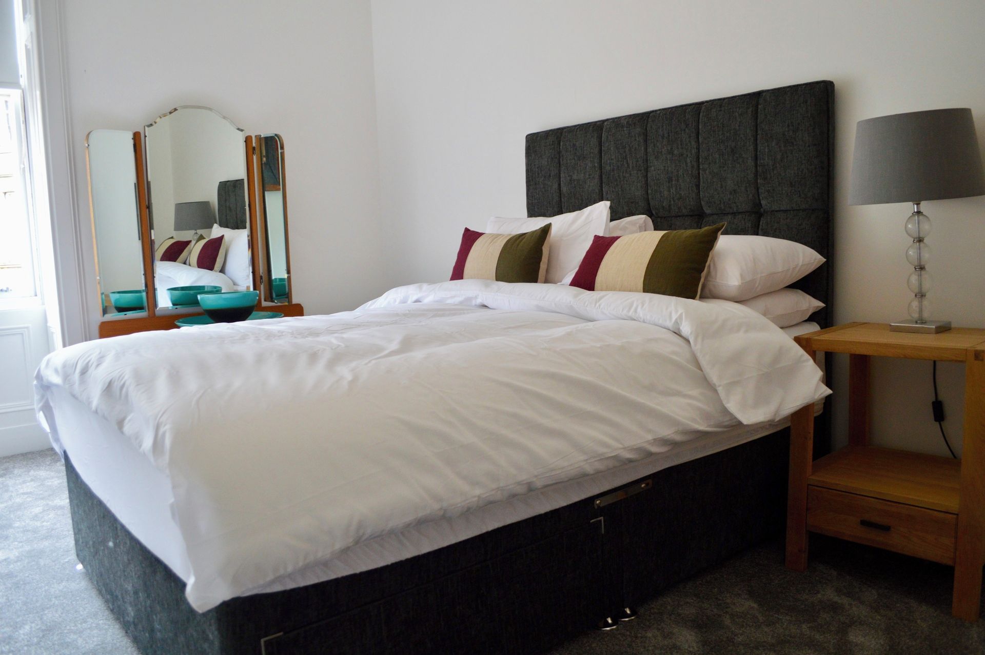 A neatly made bed with white bedding and multiple pillows in a hotel room.