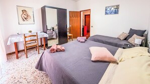 Habitación de hotel con dos camas, un escritorio, una silla, un espejo y una lámpara en el techo.