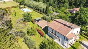 Una propiedad residencial con piscina, jardín y una casa grande con techo de tejas.