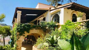 A Mediterranean-style villa with a stone archway, lush garden, and a pool area. - VILLA WITH SEA VIEWS, DIRECT ACCESS TO SEA, SWIMMING POOL AND PERFECT LOCATION (Port D'Andratx)