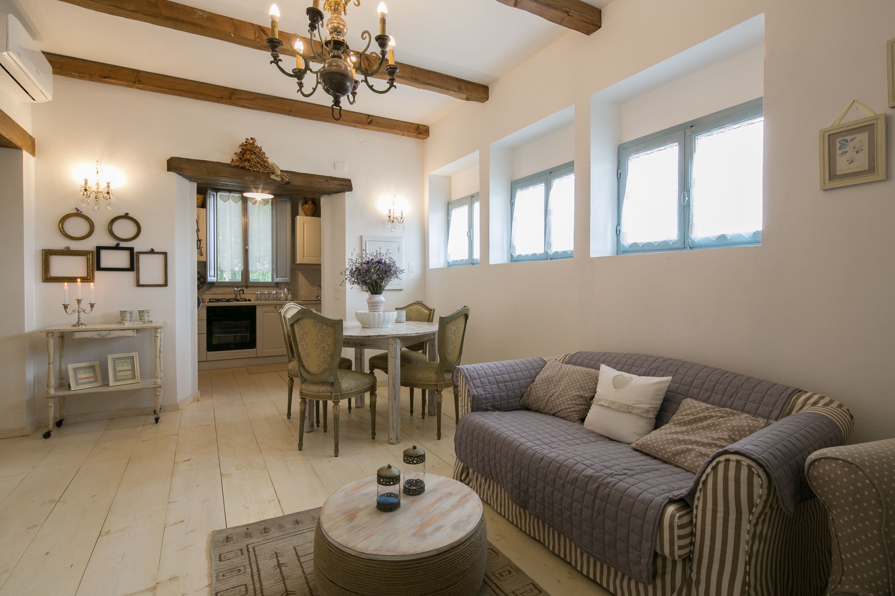 A cozy living room with a sofa, a dining table with chairs, a chandelier, and a fireplace.