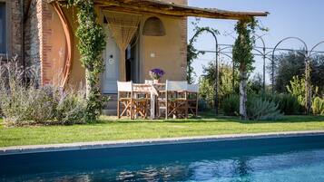 A poolside area with a pergola, outdoor seating, and a view of a pool.