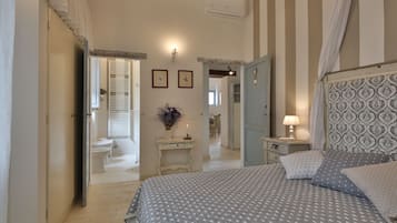 Een slaapkamer met een bed, nachtkastjes, een spiegel en een deur naar een andere kamer.