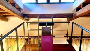 Eine Treppe mit Holell und Metallgeländer, die zu einem Balkon mit Blick auf Grünflächen führt.