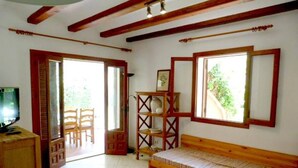 A room with a wooden bench, a white table, a TV, and a bookshelf. - Cabins 59 by homeprive (Denia)