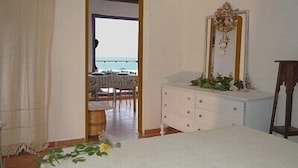 Una habitación de hotel con cama, cómoda, espejo y vista al océano.