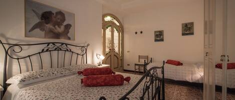 A bedroom with a large bed, a smaller bed, a chandelier, and a painting on the wall.