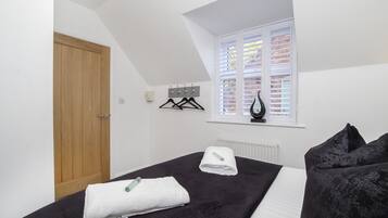 A bedroom with a bed, a window with blinds, a radiator, and a door.