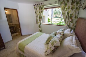 A bedroom with a bed, a window with curtains, a mirror, and an air conditioning unit. - PIÑAS 13 Tropical Holidays in Casa de Campo - 4BDR with private pool and jacuzzi (Casa de Campo)