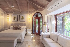 A bedroom with a bed, bedside tables, a nightstand, a sofa, a window with curtains, and a door with shutters. - PIÑAS 13 Tropical Holidays in Casa de Campo - 4BDR with private pool and jacuzzi (Casa de Campo)