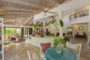 A spacious indoor area with a high ceiling, wooden beams, and a central seating area with a round table and chairs. - PIÑAS 13 Tropical Holidays in Casa de Campo - 4BDR with private pool and jacuzzi (Casa de Campo)