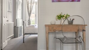 Ein Hotelzimmer mit einem Bett, einem Holztisch, einem Stuhl, einer Vase mit Blumen und einem Wandbild.