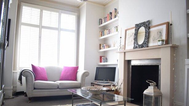 Ein Wohnzimmer mit einer Couch, einem Kamin, einem Fernseher und einem Bücherregal.