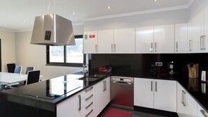 Una cocina moderna con armarios blancos, encimeras negras y electrodomésticos de acero inoxidable.