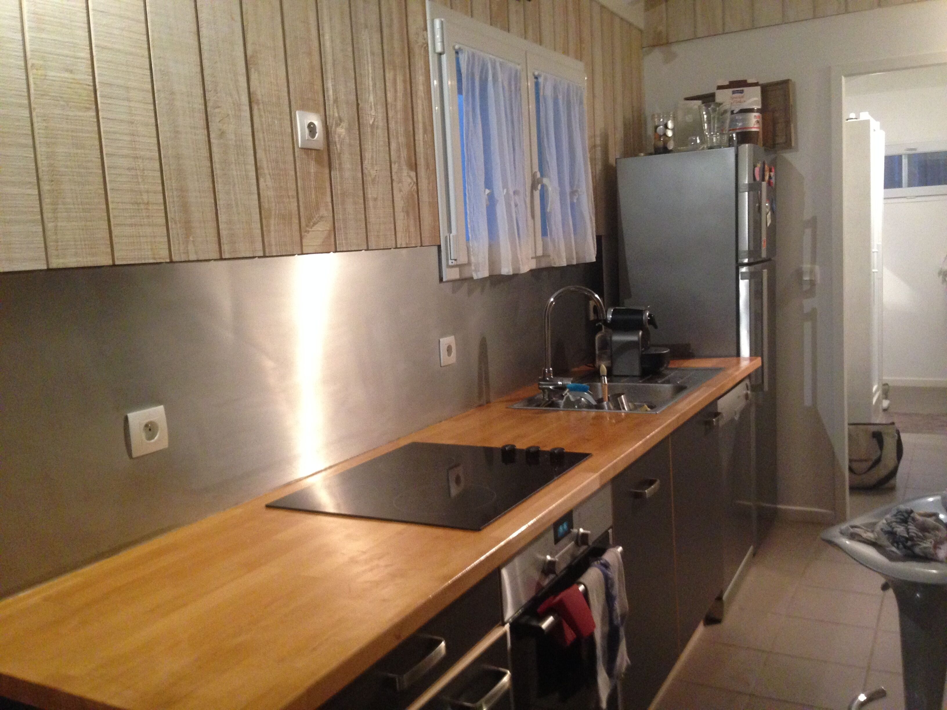 A modern kitchen with wooden cabinets, a stainless steel refrigerator, and a built-in oven.