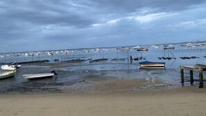 Una playa con barcos fondeados en el agua y una orilla arenosa.
