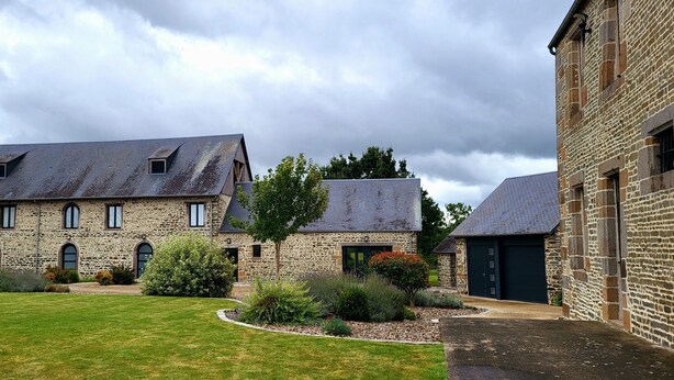 A stone building with a sloped roof, a small window, and a door. - Les lodges de la Baie Servon Mont Saint-Michel (Servon)