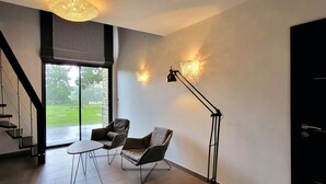 A modern interior with a staircase, two chairs, a table, and a floor lamp. - Les lodges de la Baie Servon Mont Saint-Michel (Servon)