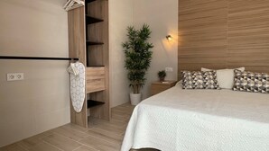 Un dormitori modern amb llit, armari, planta i tauleta de nit.