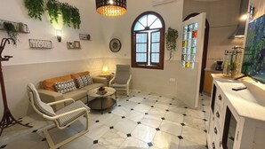 Un saló amb un sofà, una butaca i una taula de centre, una finestra gran i plantes decoratives.
