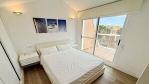 Une chambre à coucher comprenant un lit, une table de chevet, une fenêtre avec vue et un luminaire fixé au mur.
