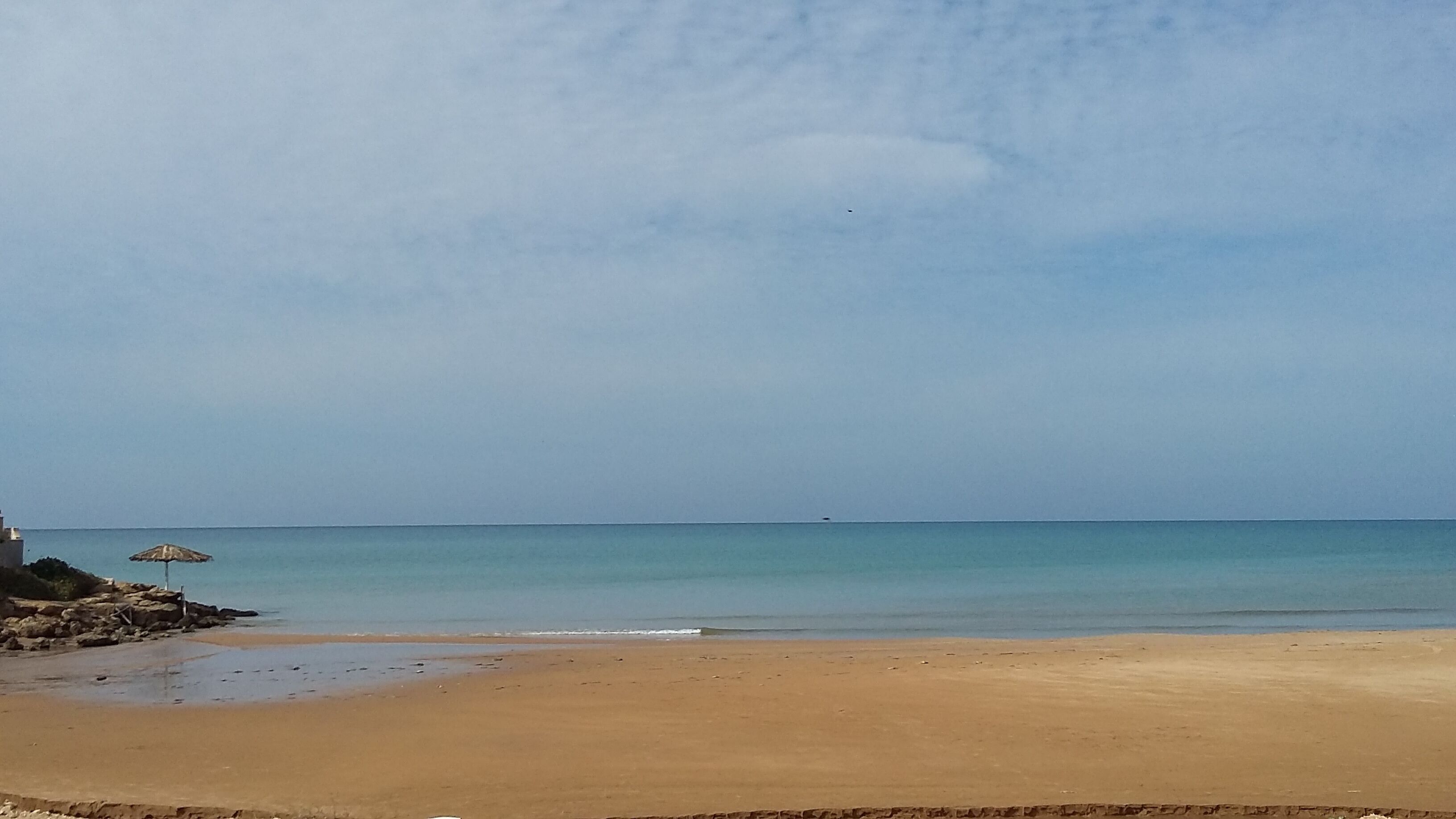 Ein Strand mit sandigem Ufer und ruhigem Wasser.