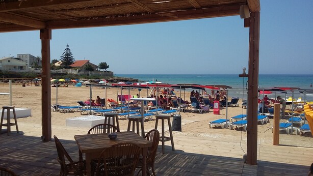 Un restaurante frente a la playa con terraza y vistas al mar.
