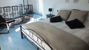 Ein Schlafzimmer mit Bett, Stuhl, Nachttisch und Fenster.